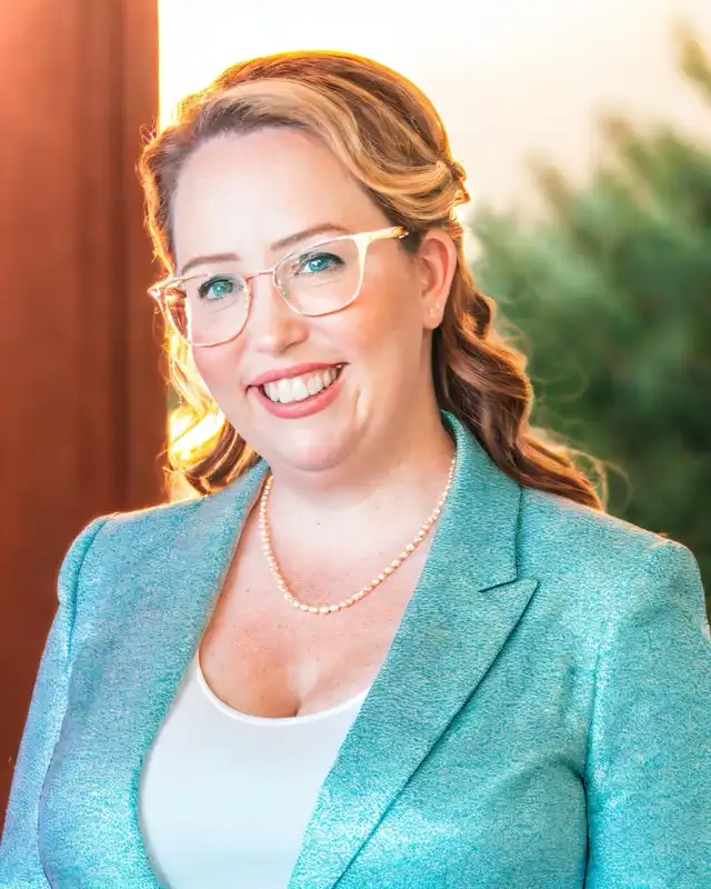 Sarah Stillinger-Karr in a teal jacket, smiling outdoors.